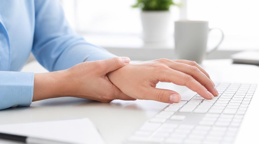 Mão de pessoa adulta apoiada sobre teclado de computador